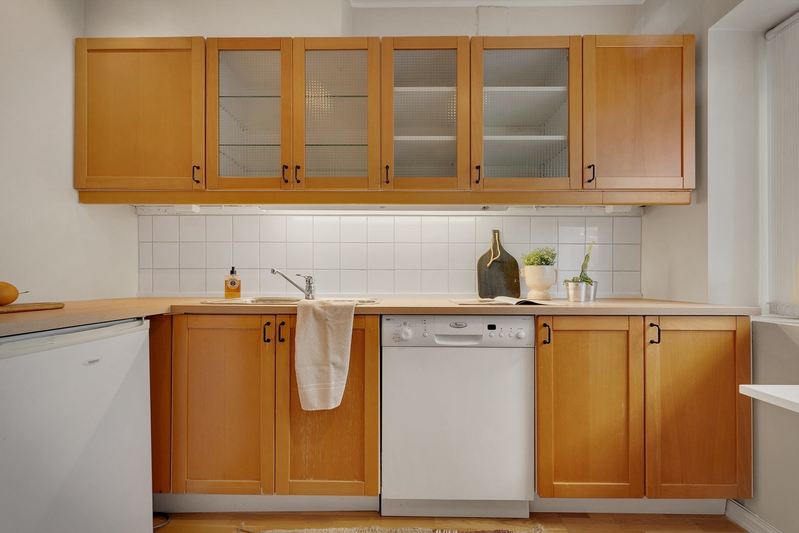 Nedfelt stålvask og hvitevarer som kjøleskap/frys, komfyr og oppvaskmaskin gjør rommet funksjonelt og brukervennlig Galleribilde