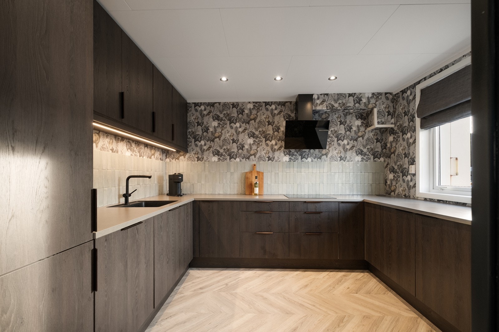 Kjøkkeninnredning med tidsriktige, mørke fronter og benkeplate med underlimt oppvaskkum. Galleribilde