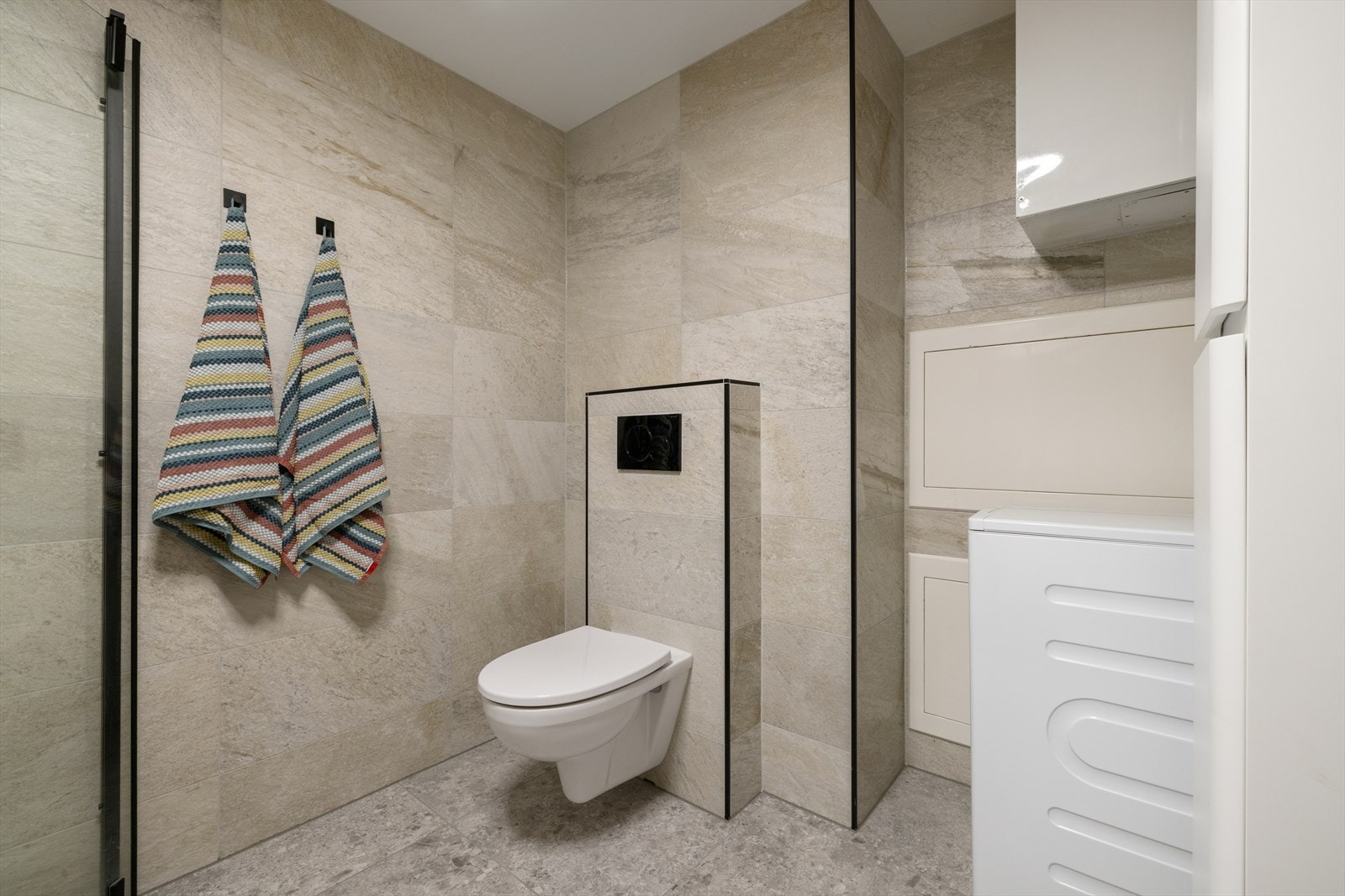 Baderommet har lekre, store fliser og et stilrent vegghengt toalett. Galleribilde