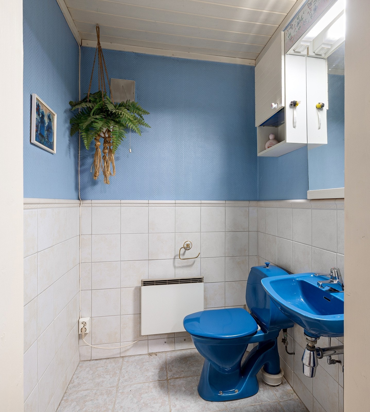 Staden 20: Toalettrom i kjeller med gulvfliser, malte tapetserte flater og fliser på vegg og malt panel i himling. Rommet består av vannklosett, servant, overskap og speil. Galleribilde