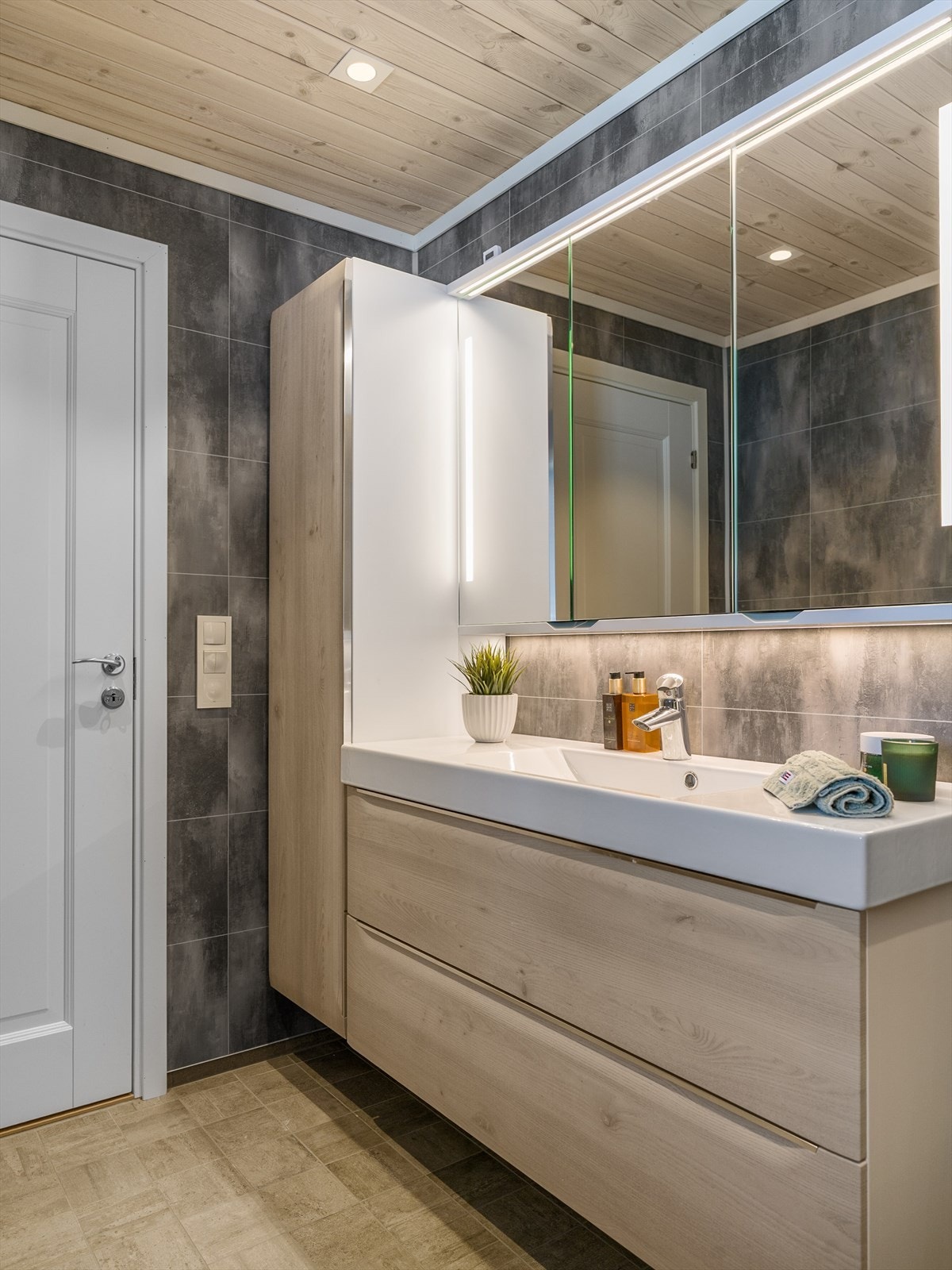 Baderommet har en stilig skuffinnredning med servant og lyssatt speil over. Galleribilde