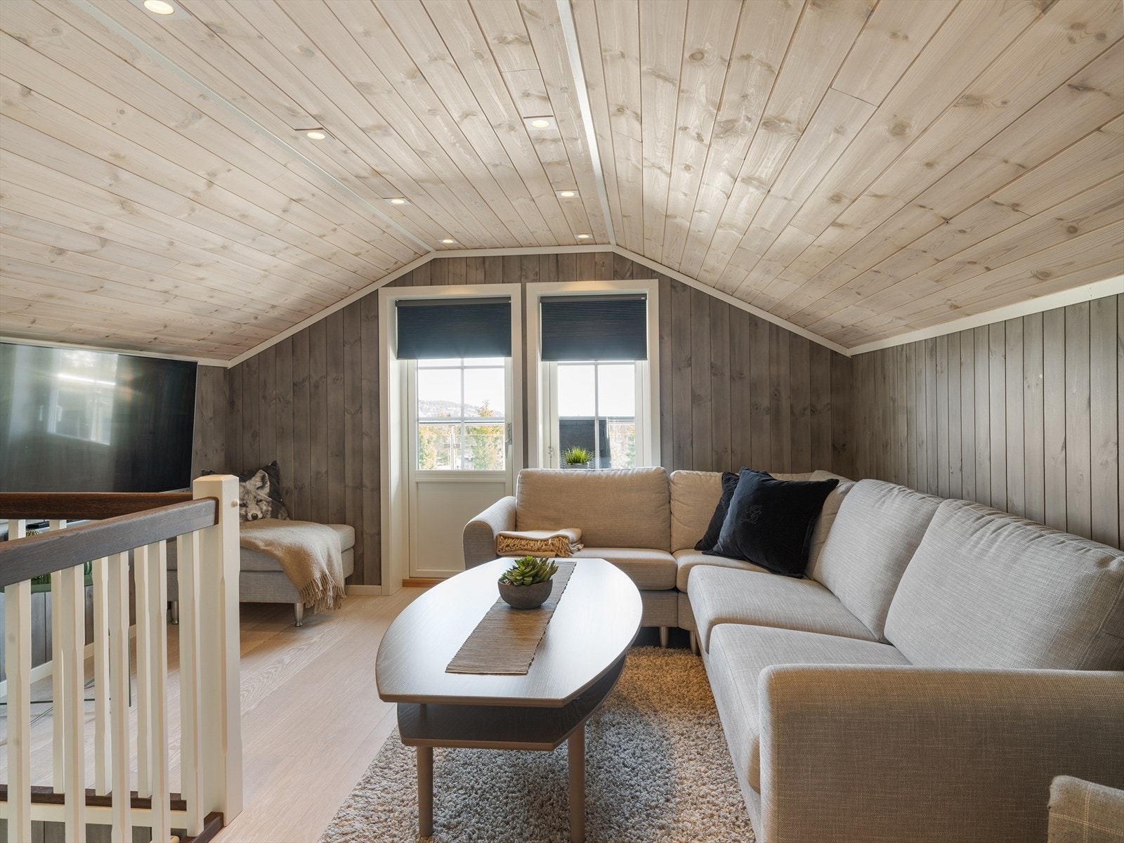 Trivelig loftstue med plass til sofagruppe og tv-seksjon. Fra stuen er det utgang til en romslig veranda med god plass til utemøbler og utsyn over nærområdet. Galleribilde