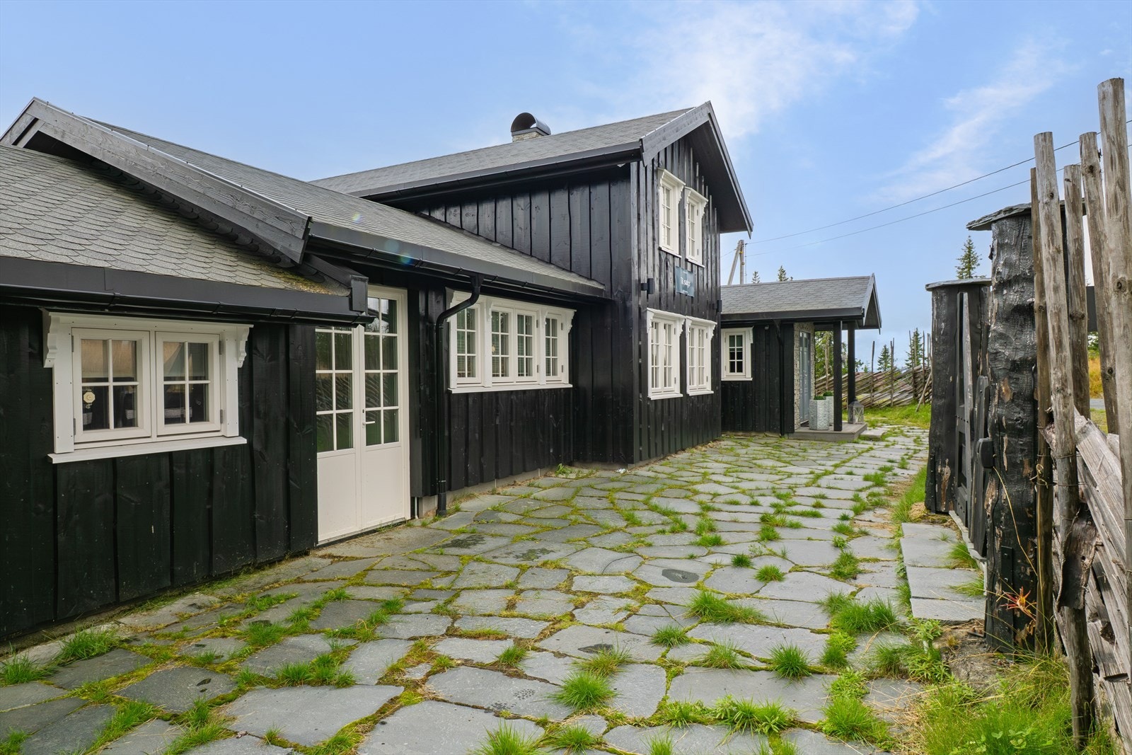 Fremsiden av hytta. Inngang både til inntilbygget anneks og hovedinngang til hytta. Galleribilde