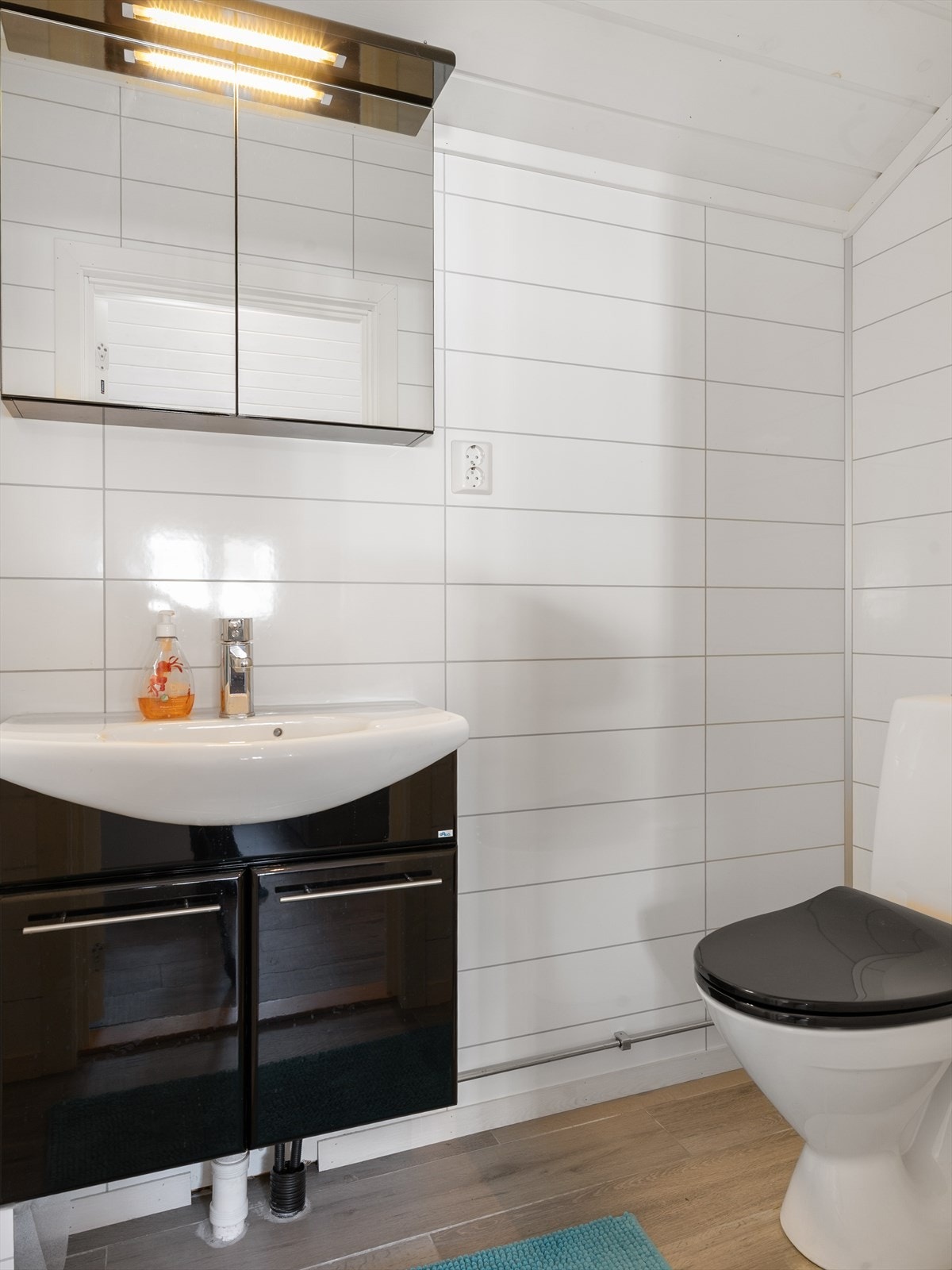 Her er det også et gjestetoalett med baderomsplater på veggene og fliser på gulv med gulvvarme. Rommet har innredning med vask og gulvstående toalett. Galleribilde