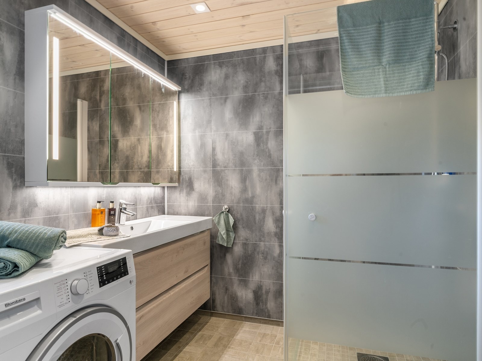 Baderom nr. 2 har baderomsplater på veggene og fliser på gulv med gulvvarme samt panel i himling med downlights. Innredning med servant, toalett, dusjhjørne samt opplegg til vaskemaskin. Galleribilde