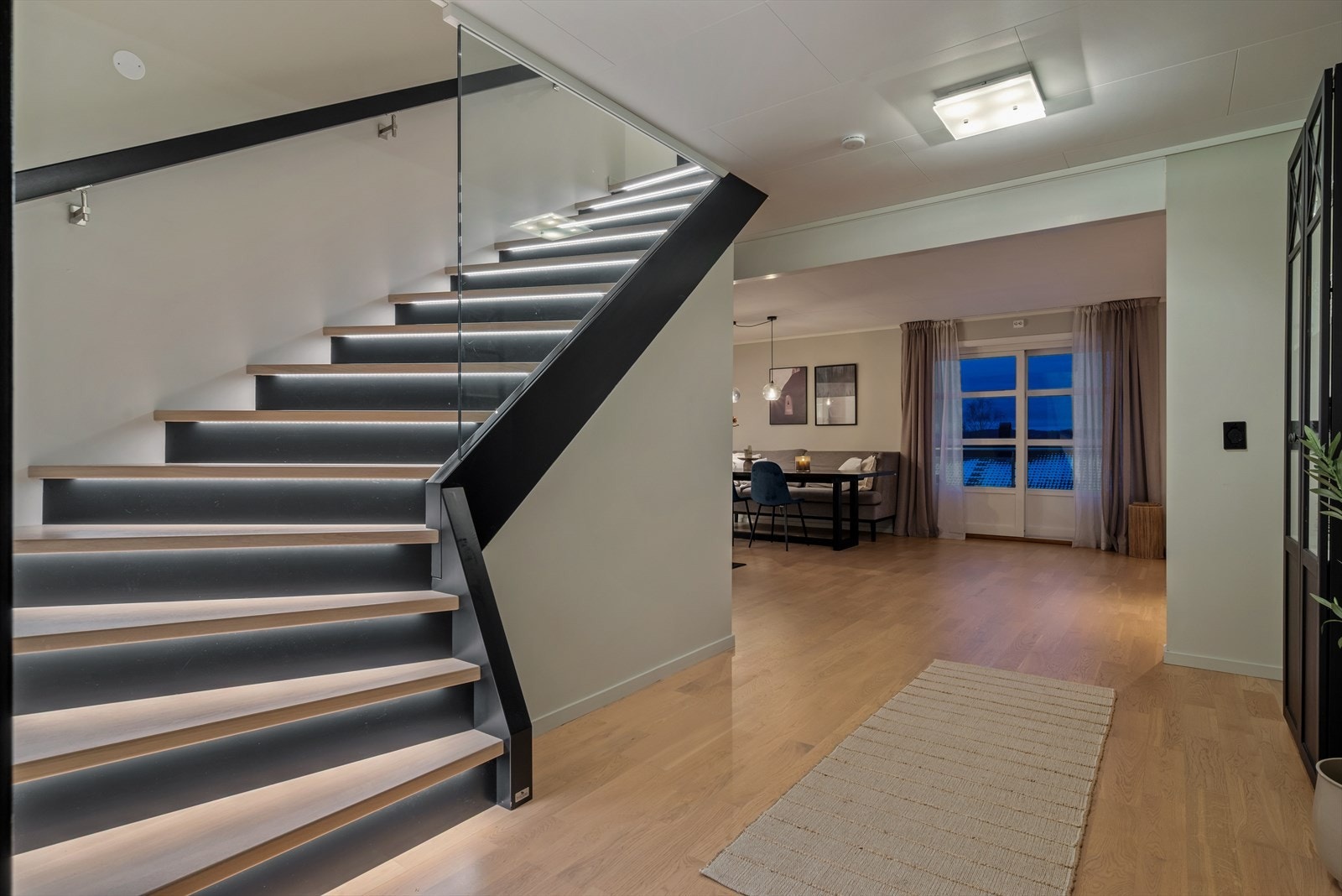 Plassbygd trapp fra 2020 fra Trappa.no, med ekstra brede trinn i hvitvasket eik, integrerte LED-lys og glassvegg. Trapperommet har lettvegger og ferdig freste spor i vangen - som gjør det enkelt å sette inn glassvegg dersom en ønsker å åpne underetasjen. Galleribilde