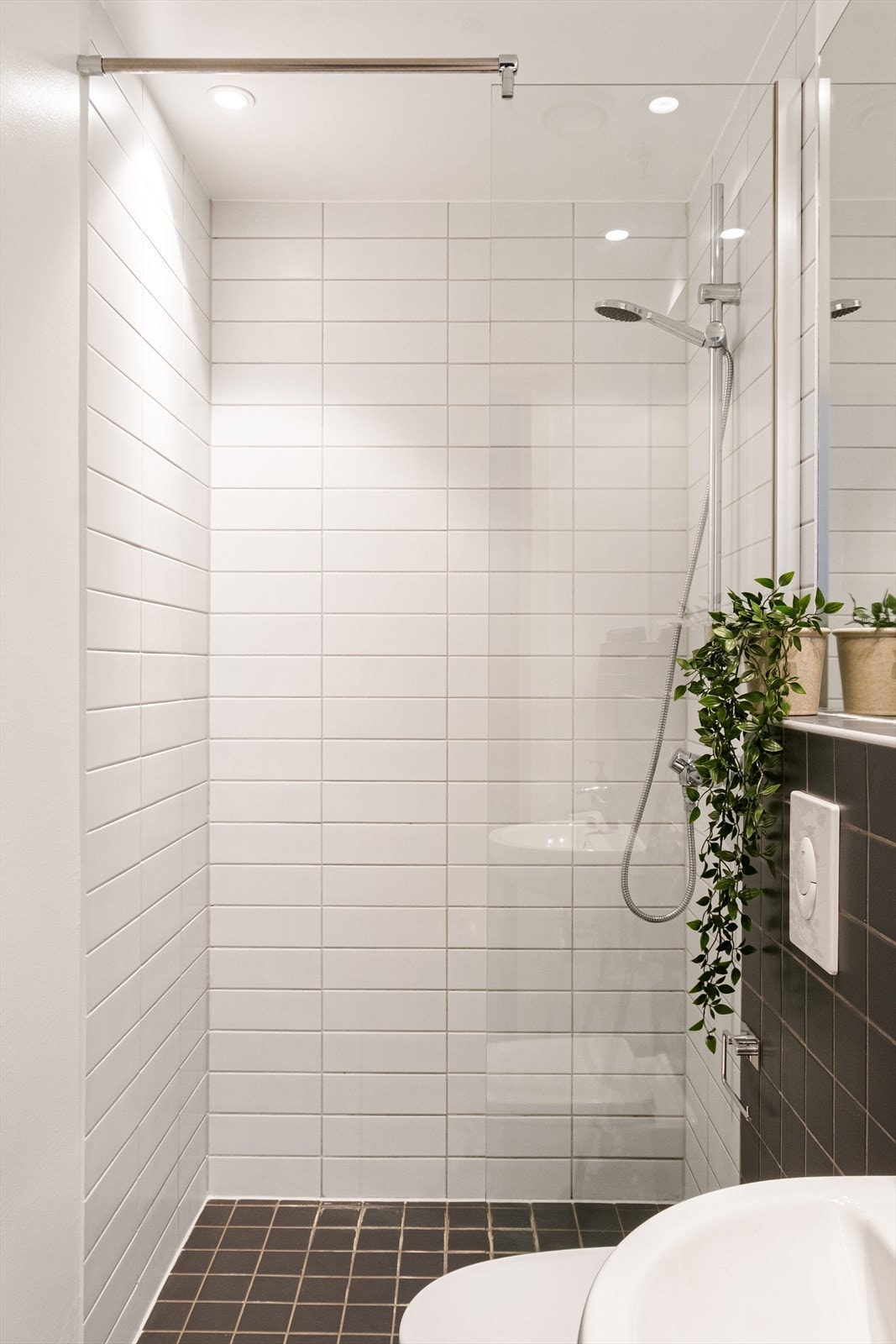 Flislagt baderom med varme i gulvet, avtrekk, speil, downlights, servant, dusj hjørne med glassvegg og vegghengt toalett. Galleribilde