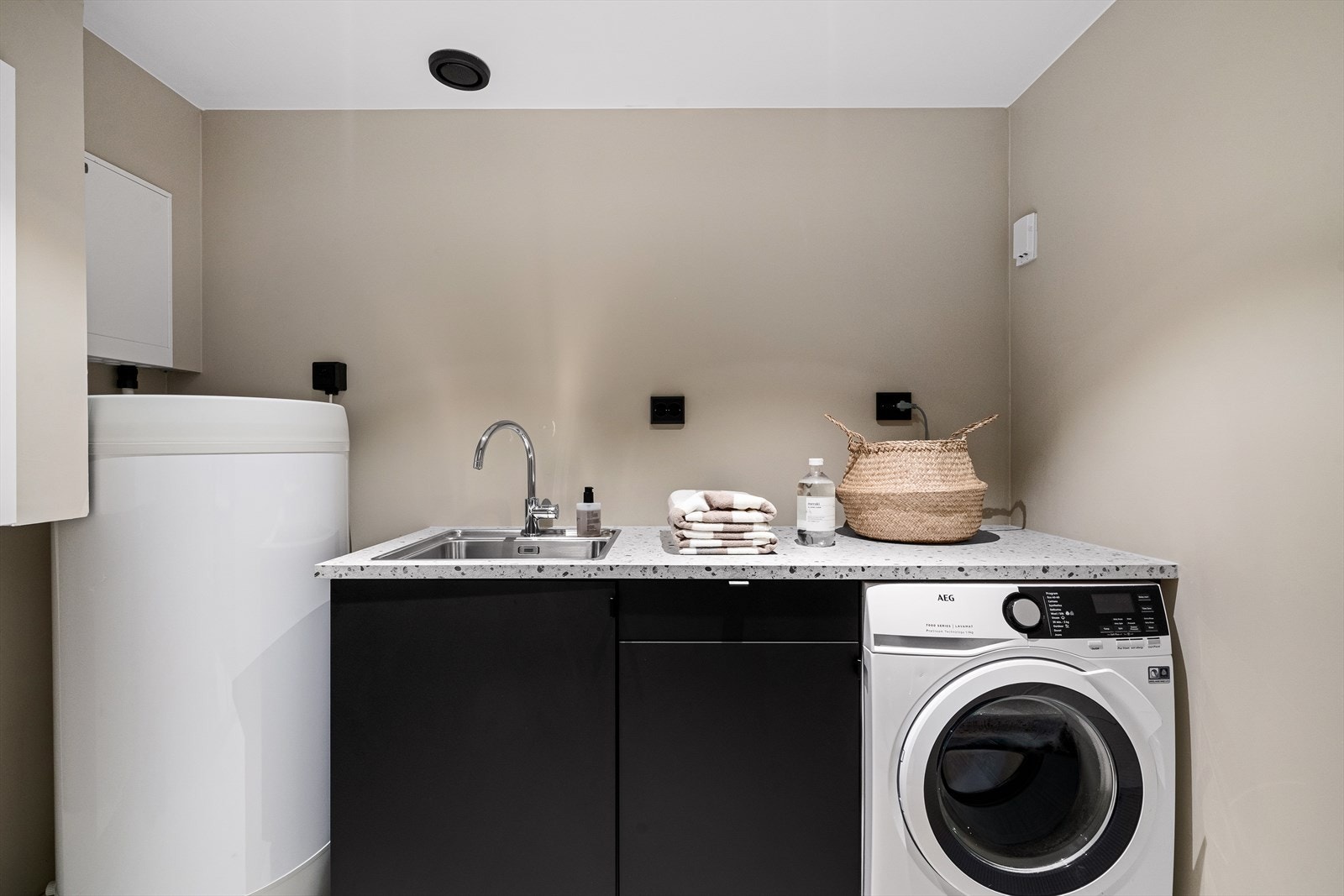 Vaskerommet har mørk innredning med vask, arbeidsbenk og opplegg for vaskemaskin/tørk. Nytt varmtvannsbereder, rør-i-rør skap m.m. Galleribilde