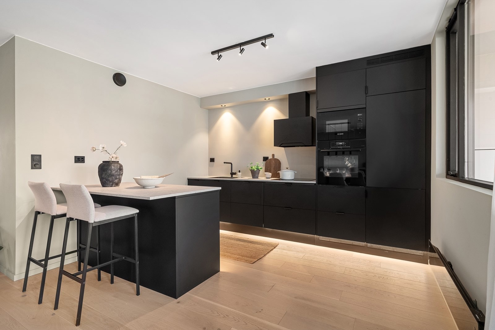 Kjøkkenet har svarte, slette fronter med lys benkeplate og integrerte hvitevarer som medfølger handelen. Galleribilde