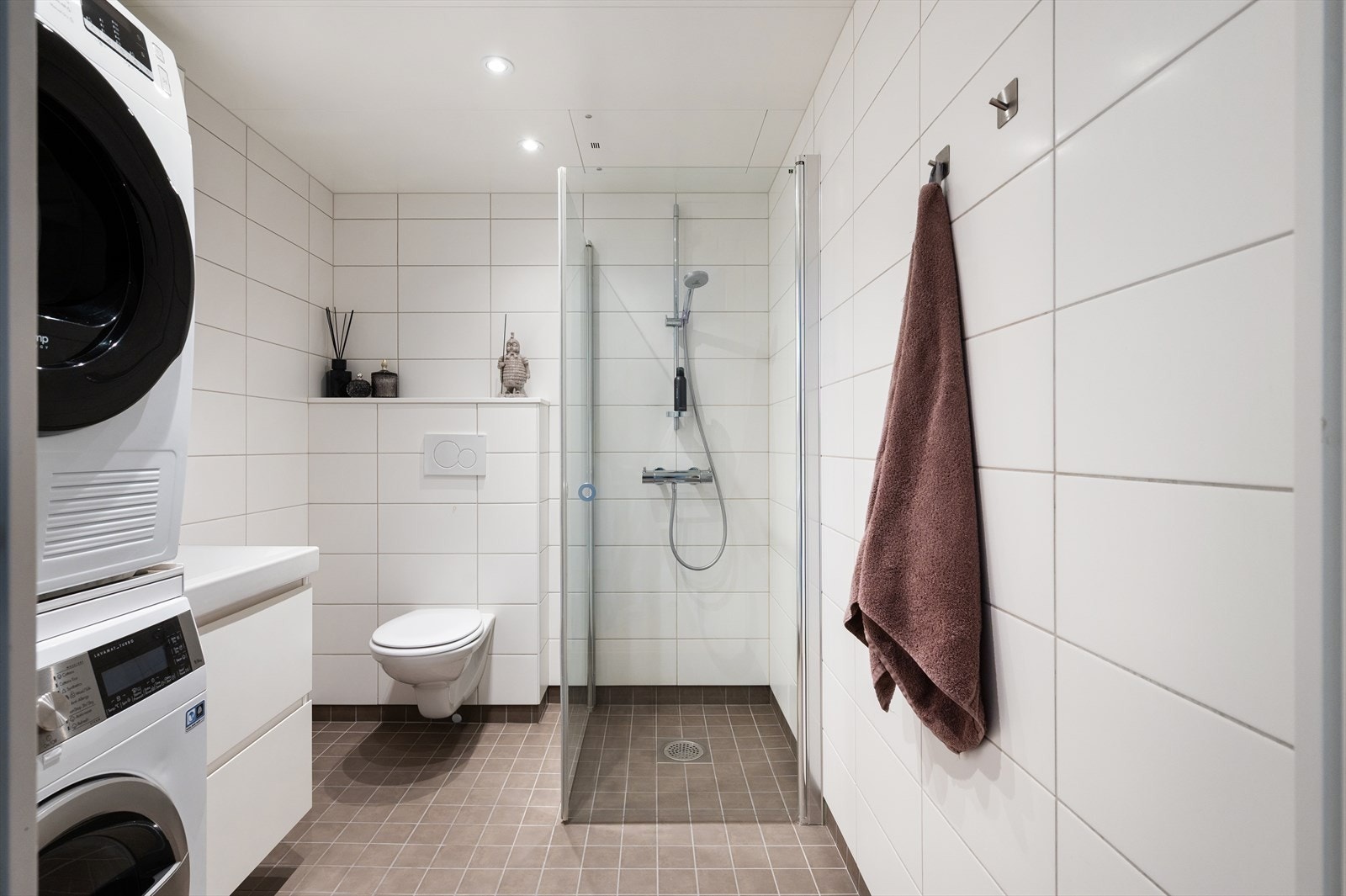 Tidsriktig baderom med vegghengt toalett, servant nedfelt i innredning, speilskap og dusjhjørne med svingbare glassdører. Galleribilde