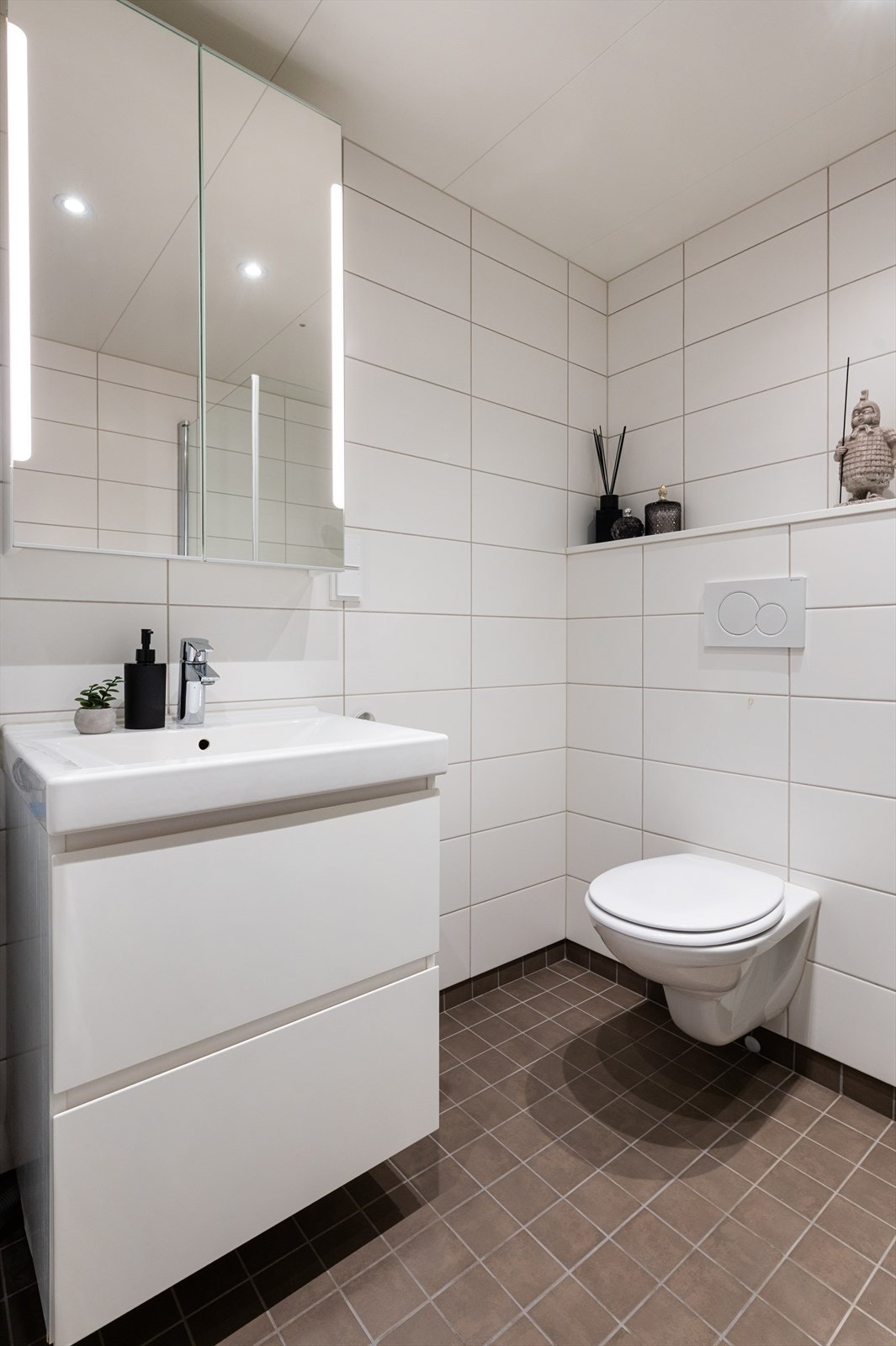 Opplegg for vaskemaskin. Baderommet har fliser på gulv og vegger, vannbåren gulvvarme, balansert ventilasjon, samt himling med lakkerte stålplater og innfelte downlights. Galleribilde