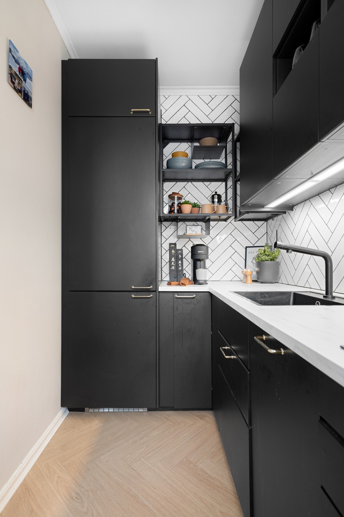 Innredningen har sorte glatte fronter og laminert benkeplate med nedfelt oppvaskkum. Både fint og praktisk med fiskebensfliser i benkeryggen og belysning under overskapene. Galleribilde