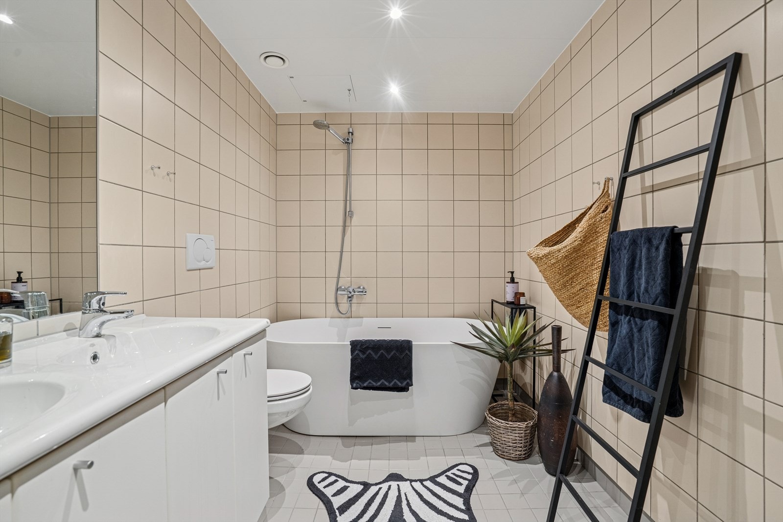 Hovedbadet er utført med flislagte overflater i nøytrale fargetoner - Her finner du badekar av nyere dato, vegghengt toalett og baderomsinnredning Galleribilde