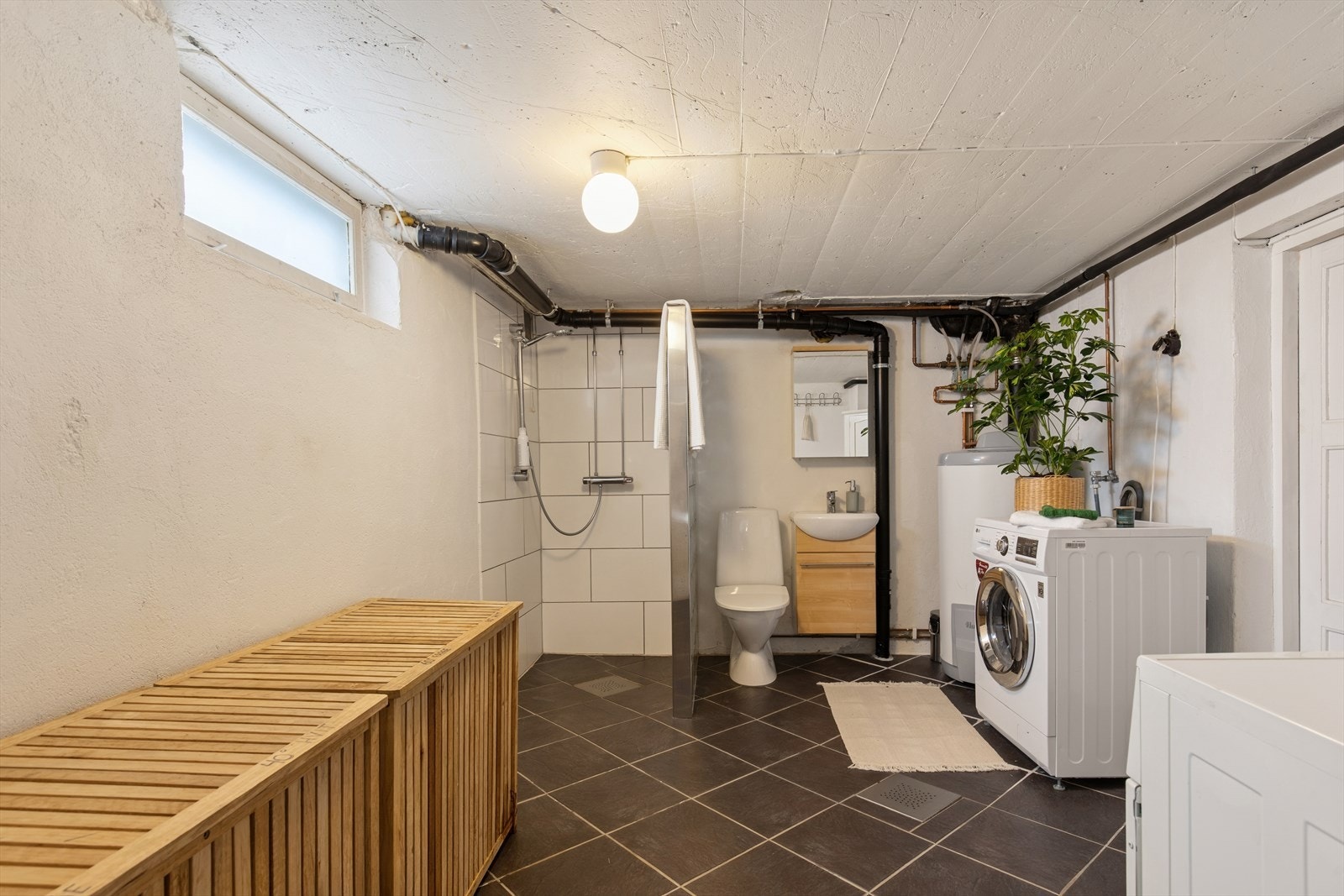 Flislagt bad/vaskerom i kjeller med dusj, toalett og baderomsinnredning. Galleribilde