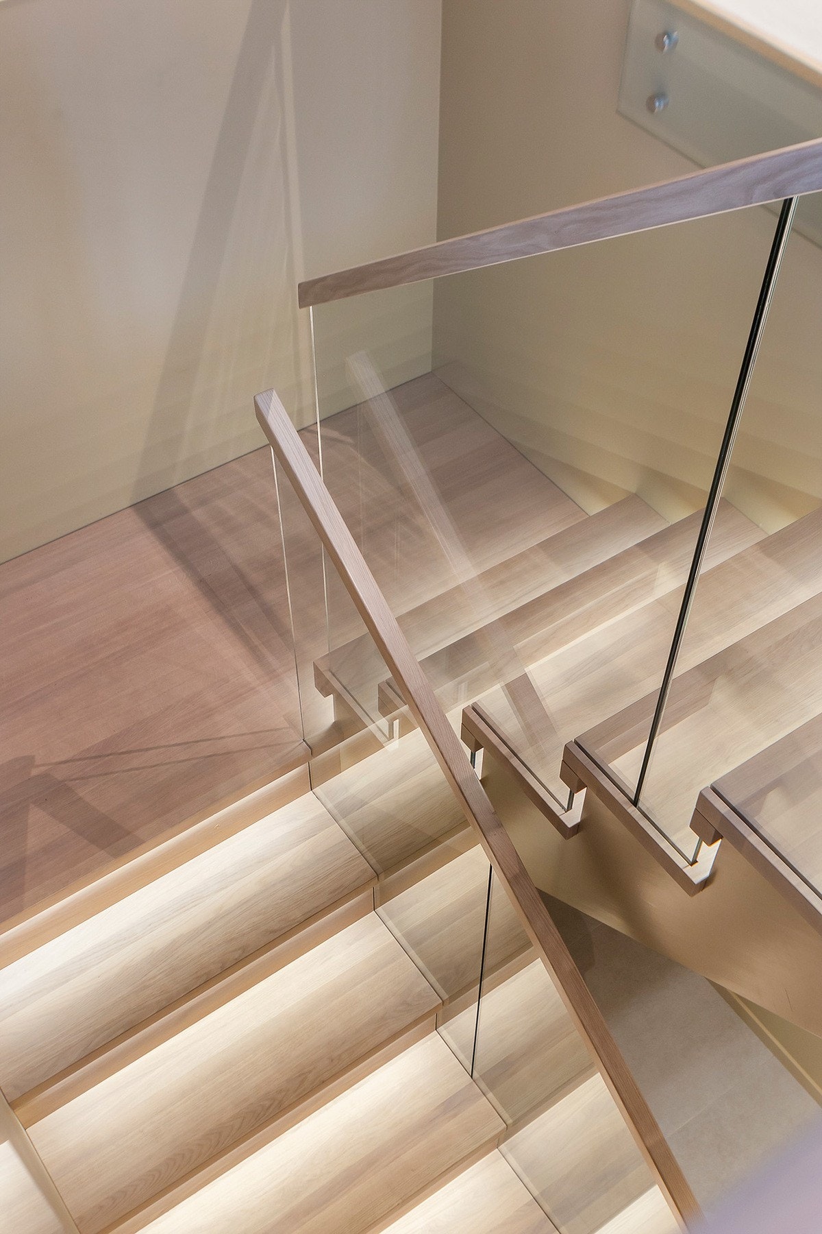 Hvitlasert eiketrapp med rekkverk i glass, ledbelysning under trappenesene og oppbevaringsrom under trapp. Galleribilde