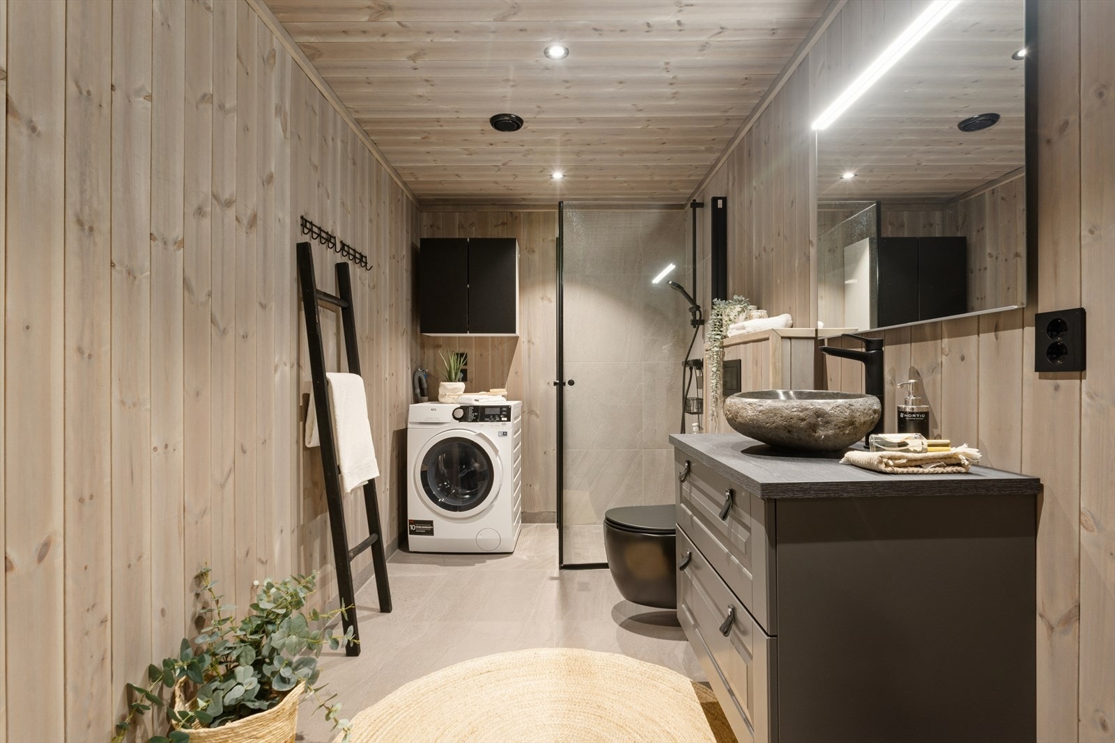 Badet har et pent uttrykk med fliser, downlights og dusj med glassdører. Galleribilde