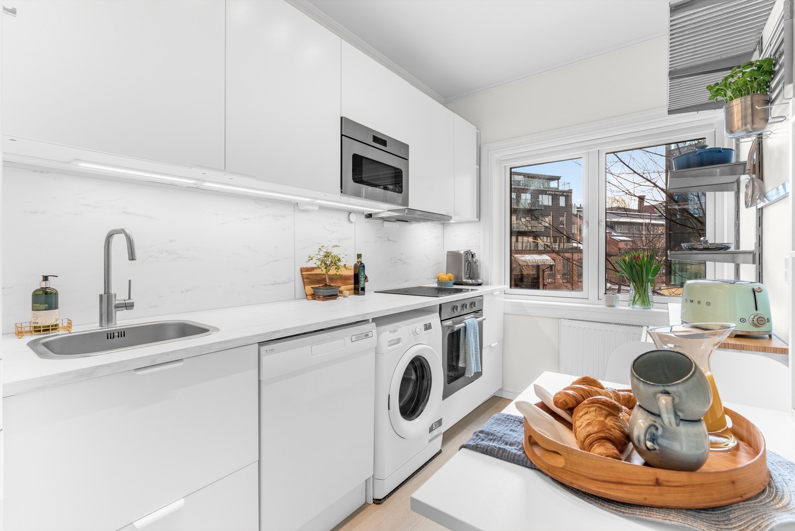 Innredningen ble montert i 2021, med hvite, glatte fronter, nedfelt oppvaskkum og hvit benkeplate av laminat i marmormønster Galleribilde