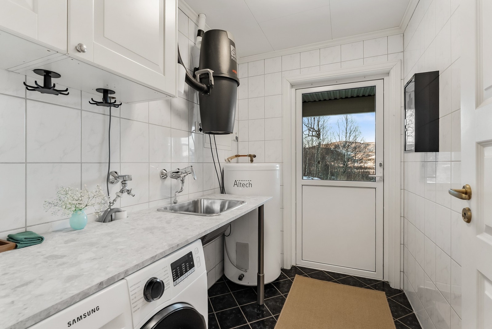 Flislagt vaskerom med varmekabler i gulvet. Innredning med nedfelt skullekar og opplegg for vaskemaskin. Utgang til terrasse og hage Galleribilde