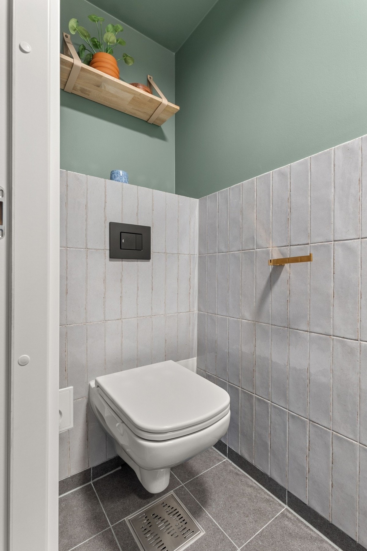 Rommet har vegg hengt klosett med innebygget sisterne, servantmøbel og speil over servant. Galleribilde