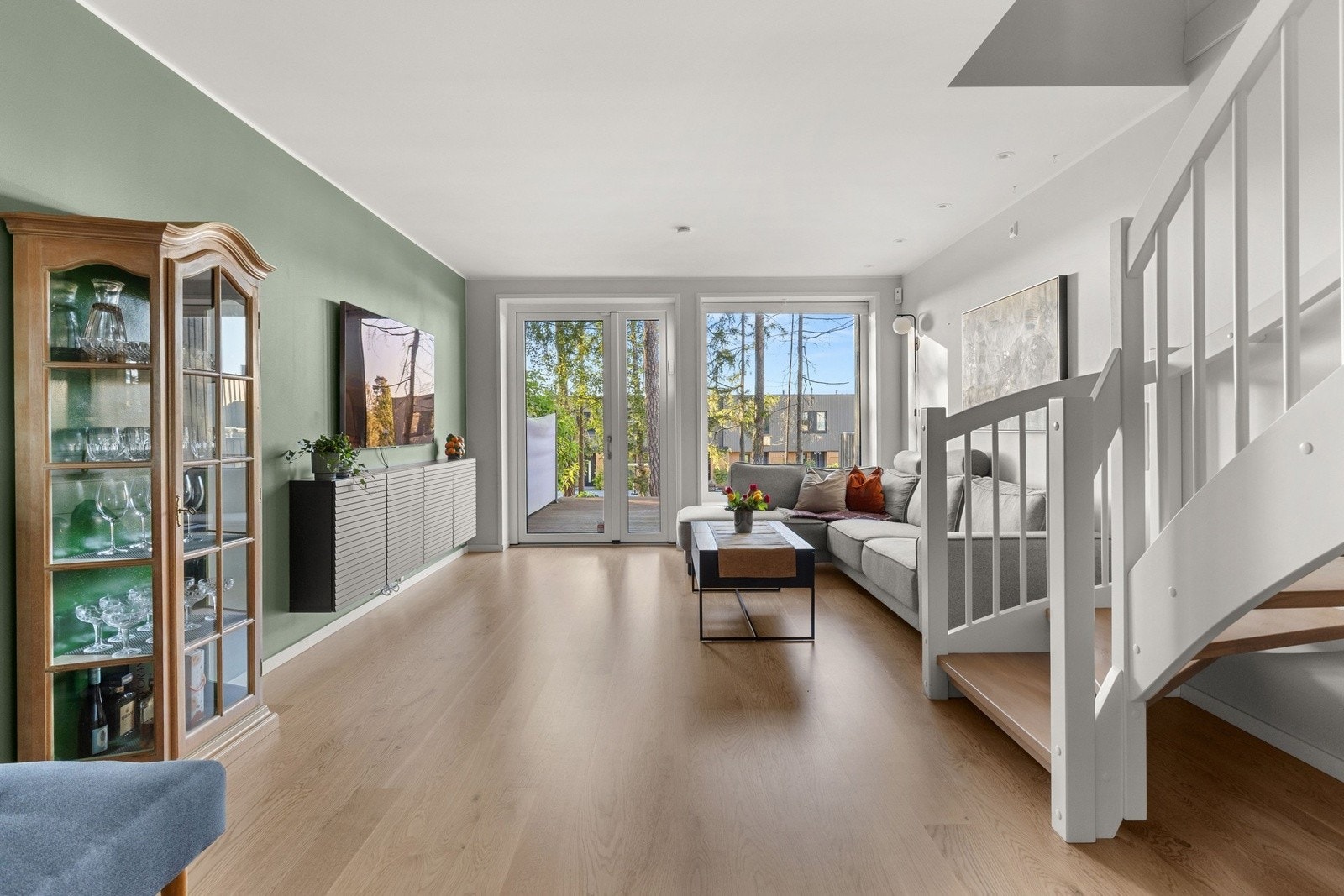 Stuen i underetasjen fremstår som et lyst og moderne oppholdsrom med god takhøyde og store vindusflater som gir rikelig med dagslys. Galleribilde