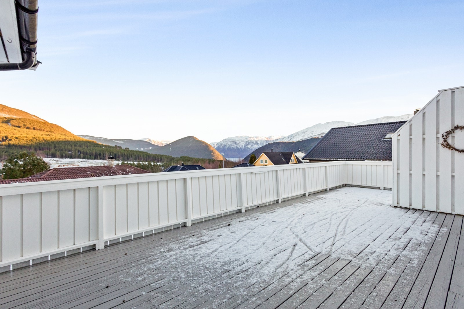 Terrassen strekker seg rundt hushjørnet med tilkomst til hagen. Galleribilde