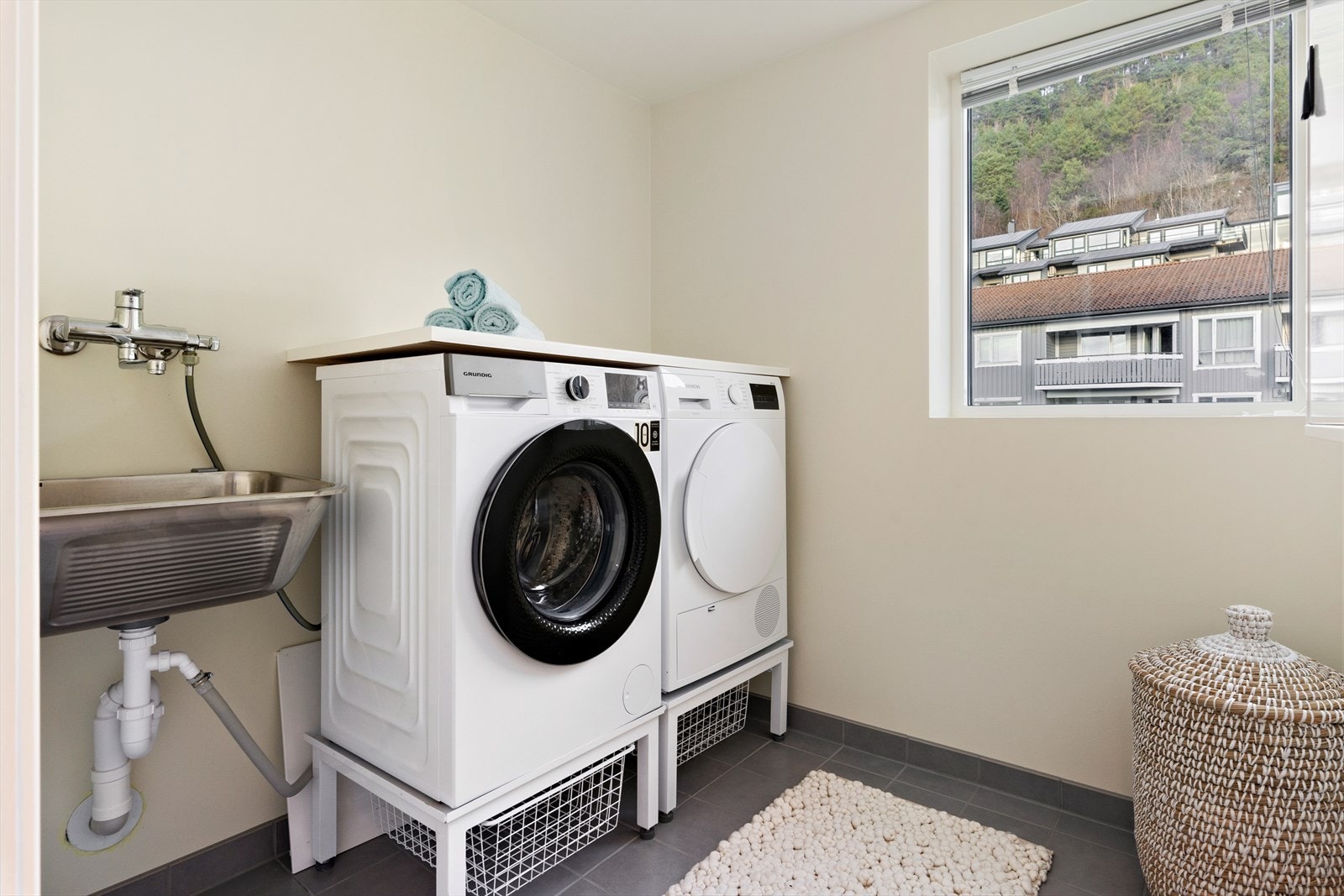 Praktisk vaskerom med fliser på gulvet. Her er opplegg for vaskemaskin og tørketrommel. Her er utslagsvask. Galleribilde