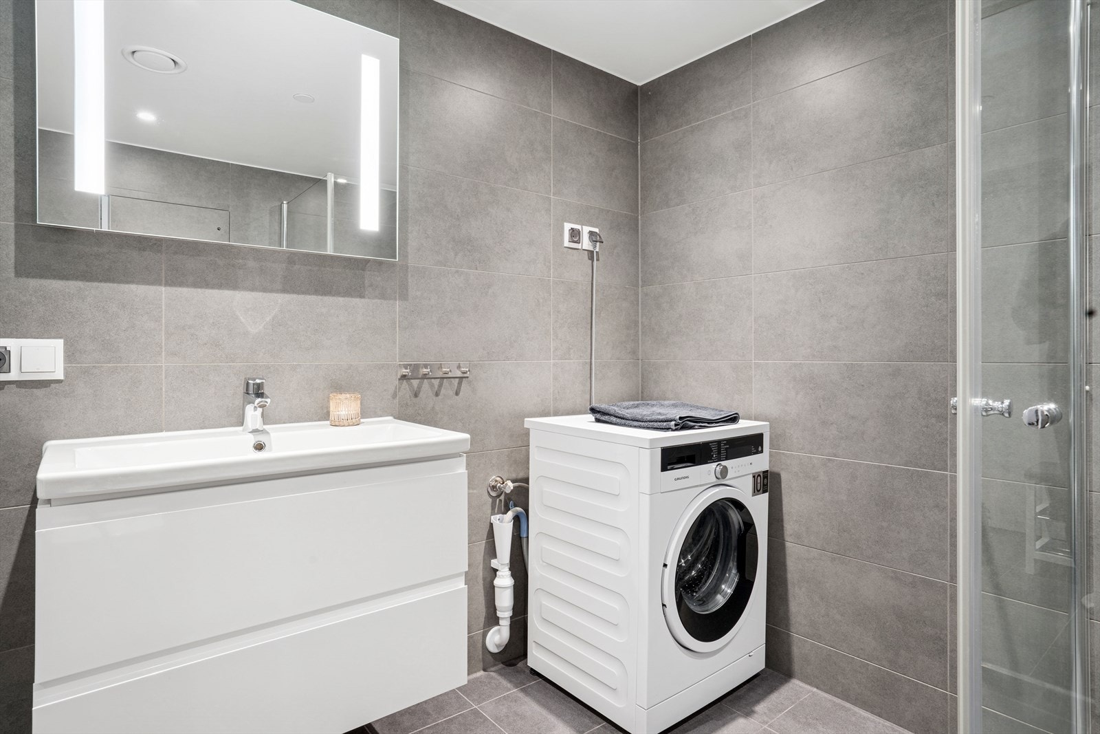 Rommet er funksjonelt innredet med servantinnredning og dusjvegger i glass. Opplegg for vaskemaskin. Galleribilde