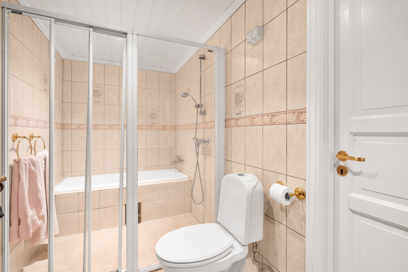 Flislagt baderom med nisje med dusj og innmurt badekar. Galleribilde