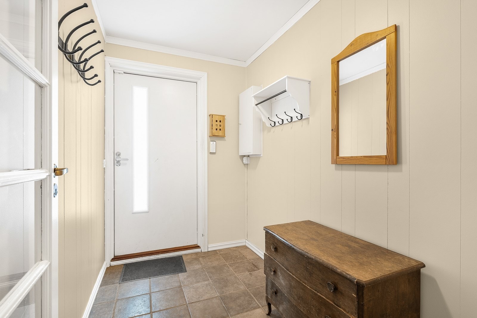 Flislagt entré med lyse overflater og rikelig med veggplass til knaggrekker og oppheng. Galleribilde