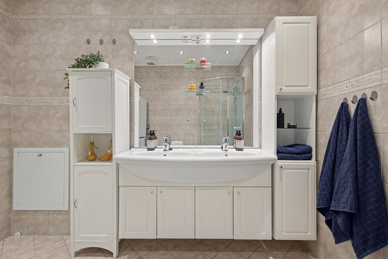 Stor baderomsinnredning med to nedfelte servanter,, speil med tilhørende belysning og høyskap. Galleribilde