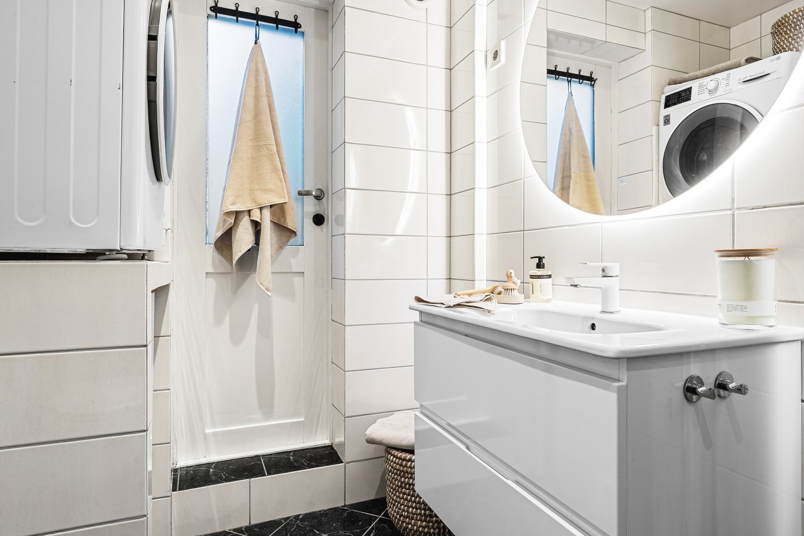 Badet er innredet med dusj, vegghengt toalett, servant med underskap, speil med lys, varmtvannstank og opplegg for vaskemaskin. Galleribilde