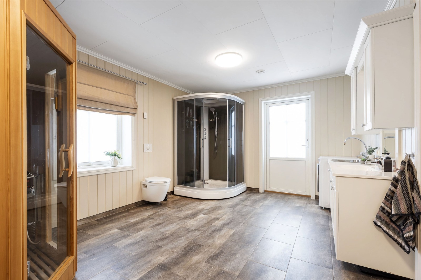 Særdeles romslig bad/vaskerom med dusjkabinett (nytt), wc, badstue og innredning med servant og utslagsvask Galleribilde