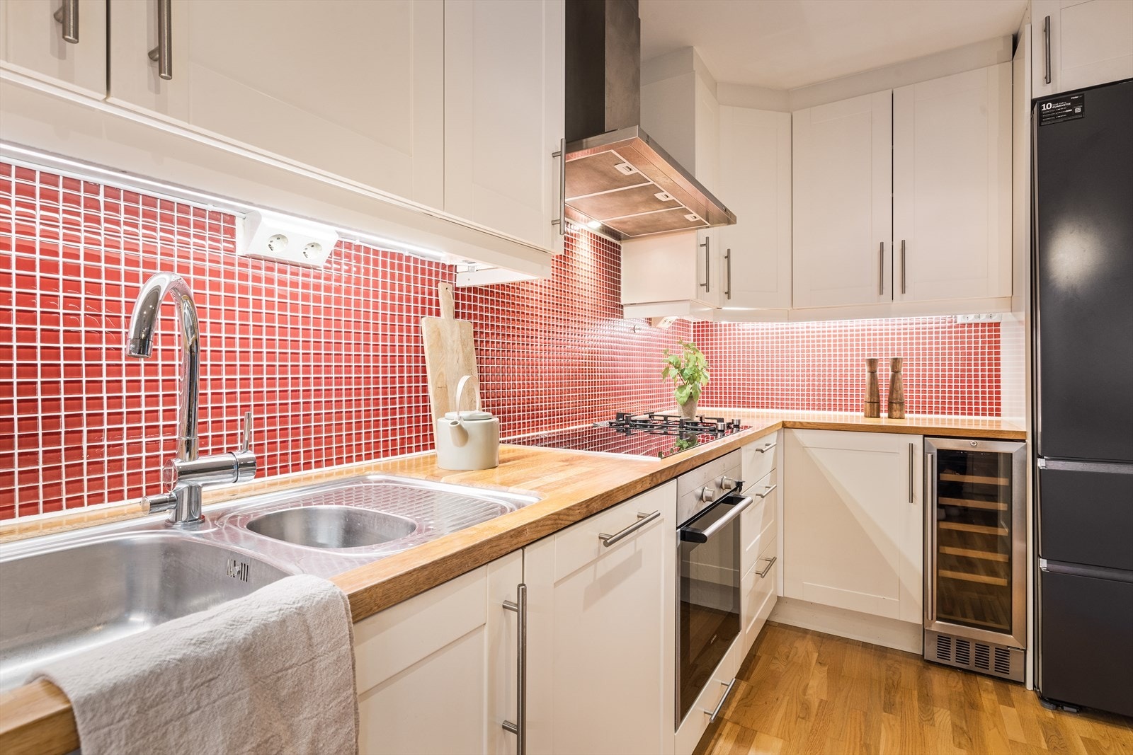 Kjøkkenet er blitt innredet med integrerte hvitevarer som stekeovn, koketopp med delvis gassfunksjon, ventilator, oppvaskmaskin, vinskap og frittstående kjøl- og fryseskap. Galleribilde