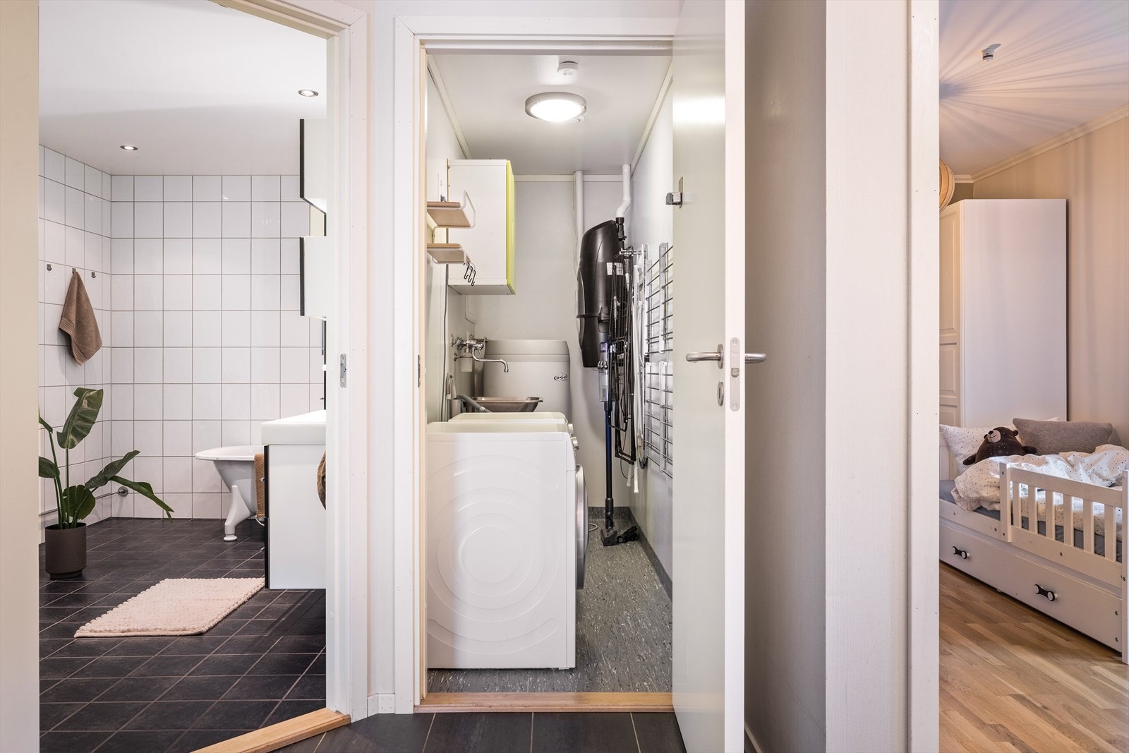 Praktisk vaskerom med opplegg for vaskemaskin og tørketrommel. Her har man også sentralstøvsuger og oppbevaringsmuligheter. Galleribilde