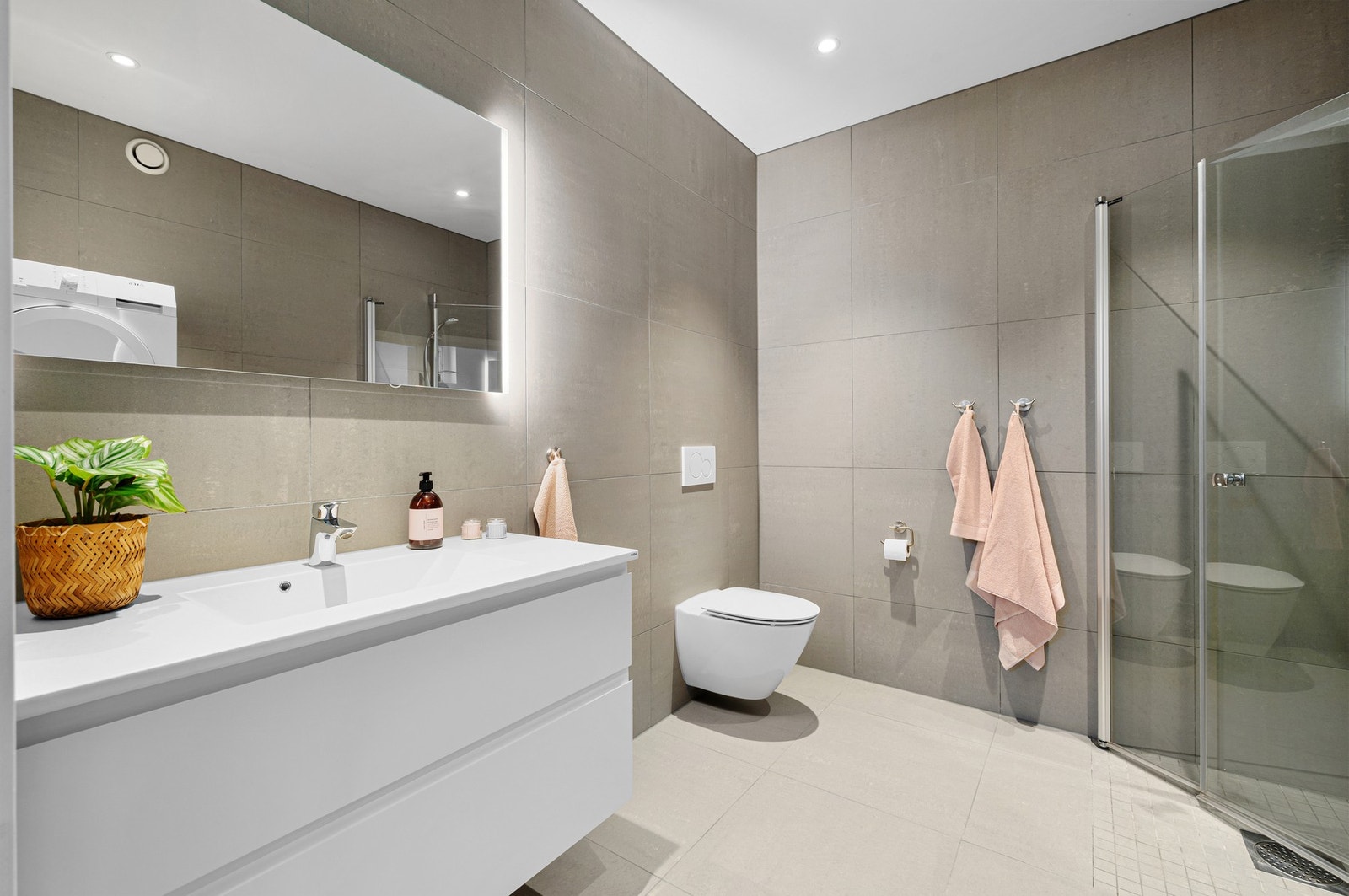 Badet er innredet med matt støpt marmorsservant og speil med integrert LED-belysning. Baderomsinnredningen fra HTH er utvidet i bredde for ekstra oppbevaringsplass. Videre har rommet veggmontert toalett og et stilrent dusjhjørne. Galleribilde