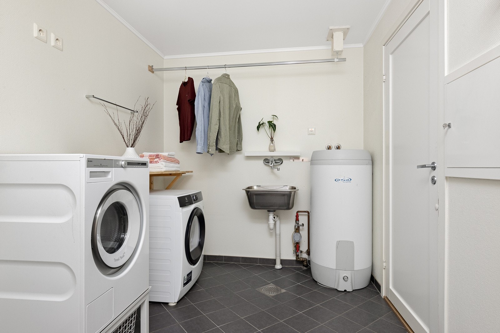 Praktisk vaskerom med flislagt gulv, varmekabler og opplegg for vaskemaskin. Galleribilde