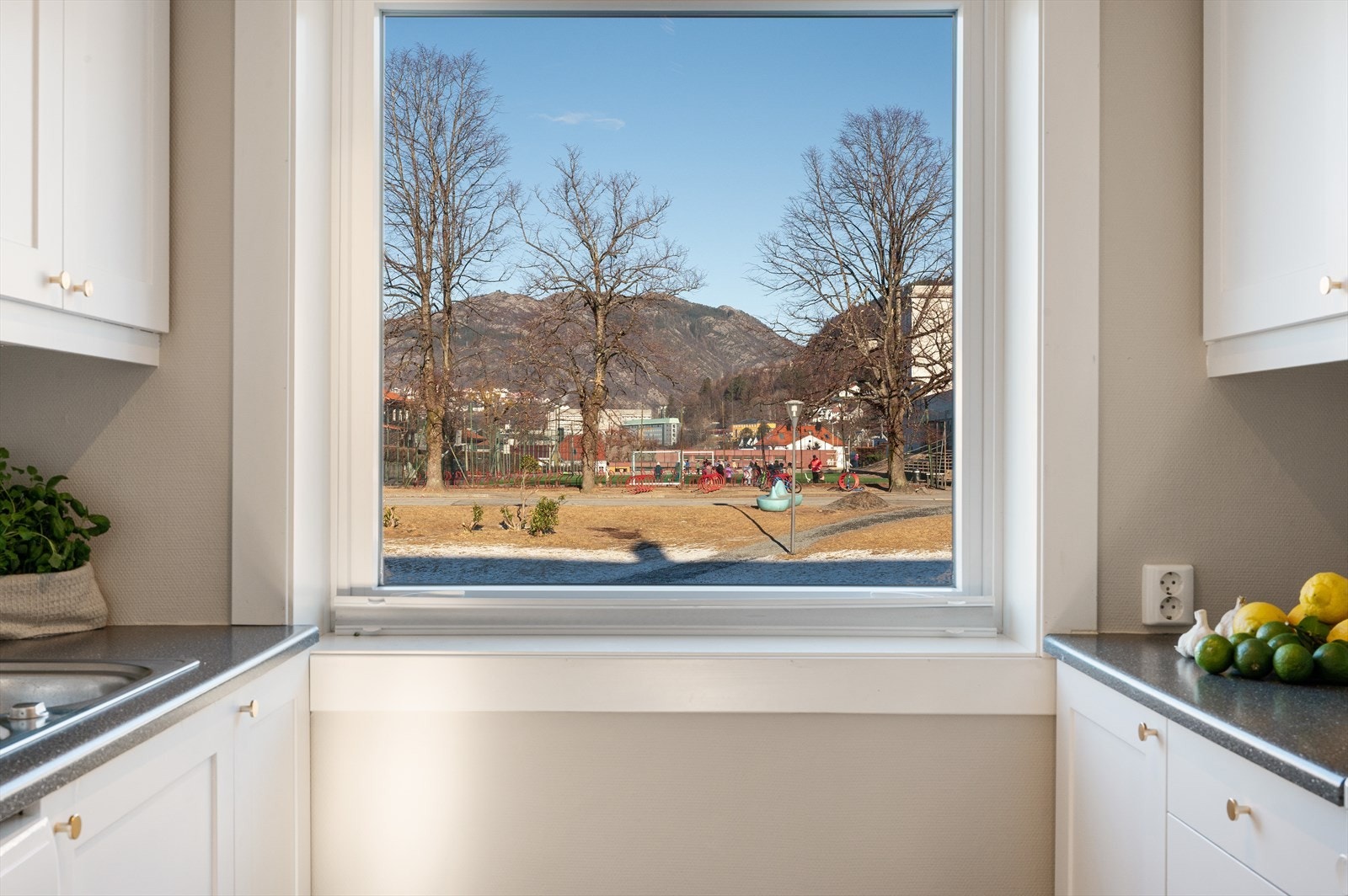 - Tidløs kjøkkeninnredning med hvite fronter og benkeplate i laminat. Merk stikkontakt over benkeplate - Galleribilde