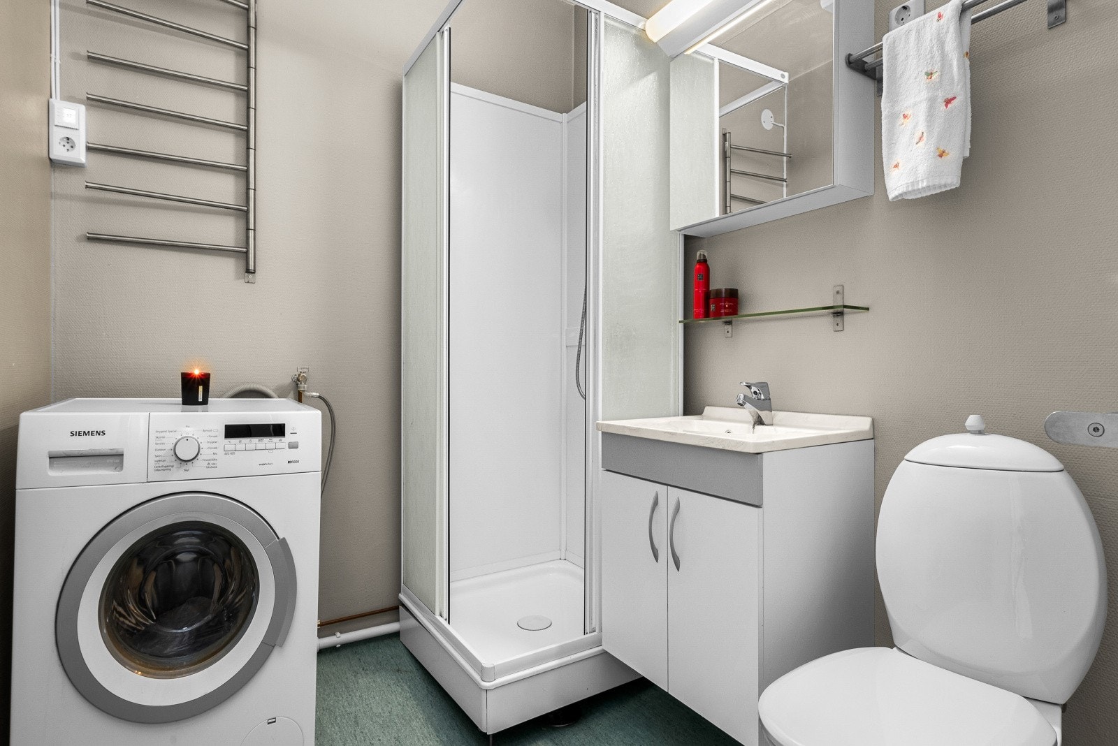 Badet er utstyrt med dusjkabinett, mekanisk avtrekk, toalett, opplegg for vaskemaskin og servant i skap, samt elektrisk gulvvarme. (Vaskemaskin medfølger i handelen om ønskelig). Galleribilde