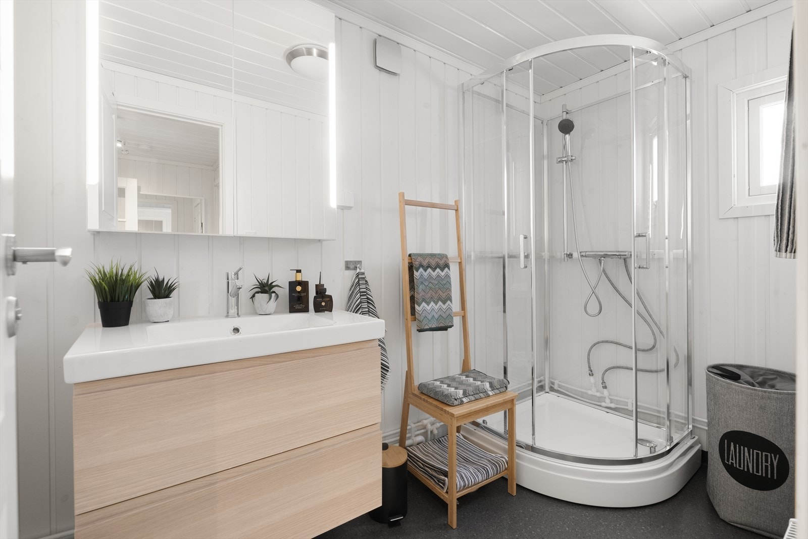 Hytta har et lyst og pent bad fra 2016. Badet har belegg på gulv og panel på vegger. Her er det dusjkabinett og innredning med heldekkende hvit vask, underskuffer med slette fronter og speil med lys. Elektrisk styrt vifte. Galleribilde