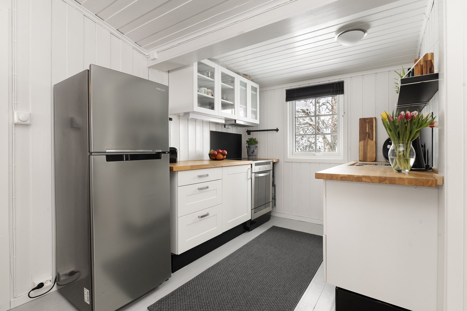 Det er åpen løsning inn mot kjøkkenkroken, og hele rommet har tregulv og panel på vegger. Galleribilde