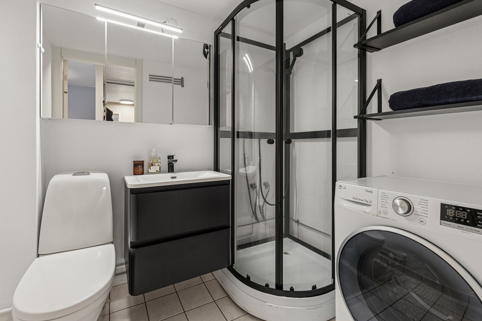 Innredningen består av en seksjon med glatte fronter, heldekkende servant og et speilskap med belysning. Videre er rommet utstyrt med et gulvstående toalett, et dusjkabinett, samt opplegg for vaskemaskin. Galleribilde