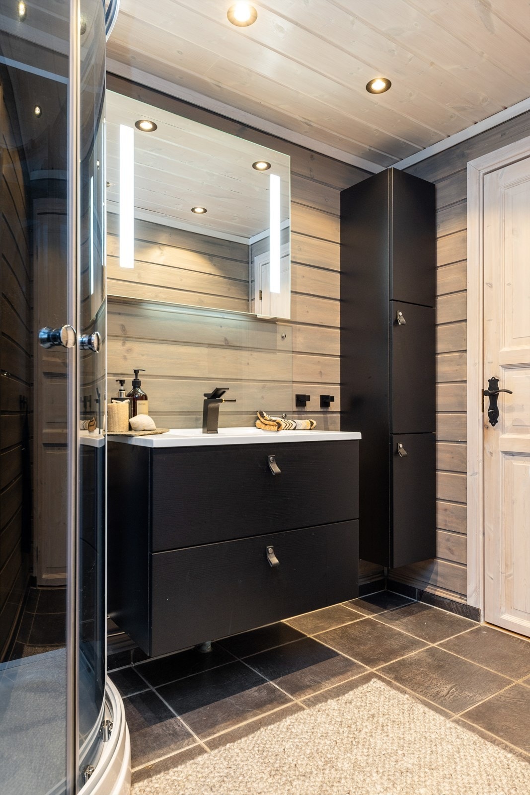 Praktisk baderomsinnredning med servant, toalett, dusjkabinett og opplegg for vaskemaskin Galleribilde