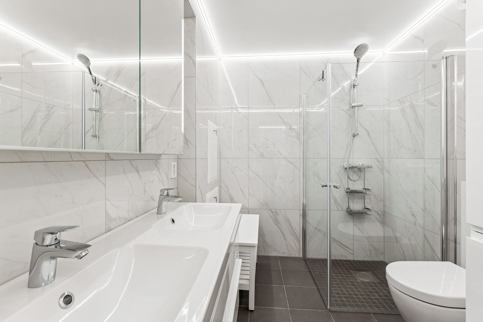 Flislagt bad med varme i gulv, innfellbare dusjdører og vaskemaskin og tørketrommel som følger med Galleribilde