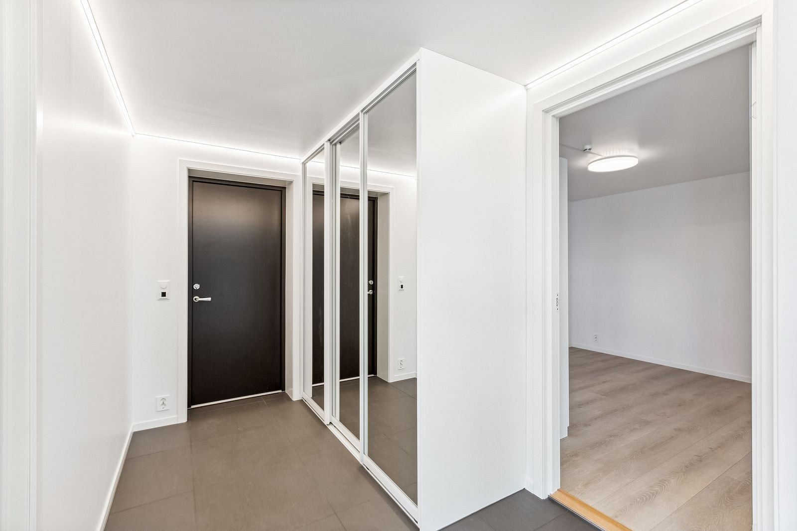 Romslig entre med praktisk skyvedørsgarderobe med innredning for oppbevaring av yttertøy, sko m.m. Galleribilde