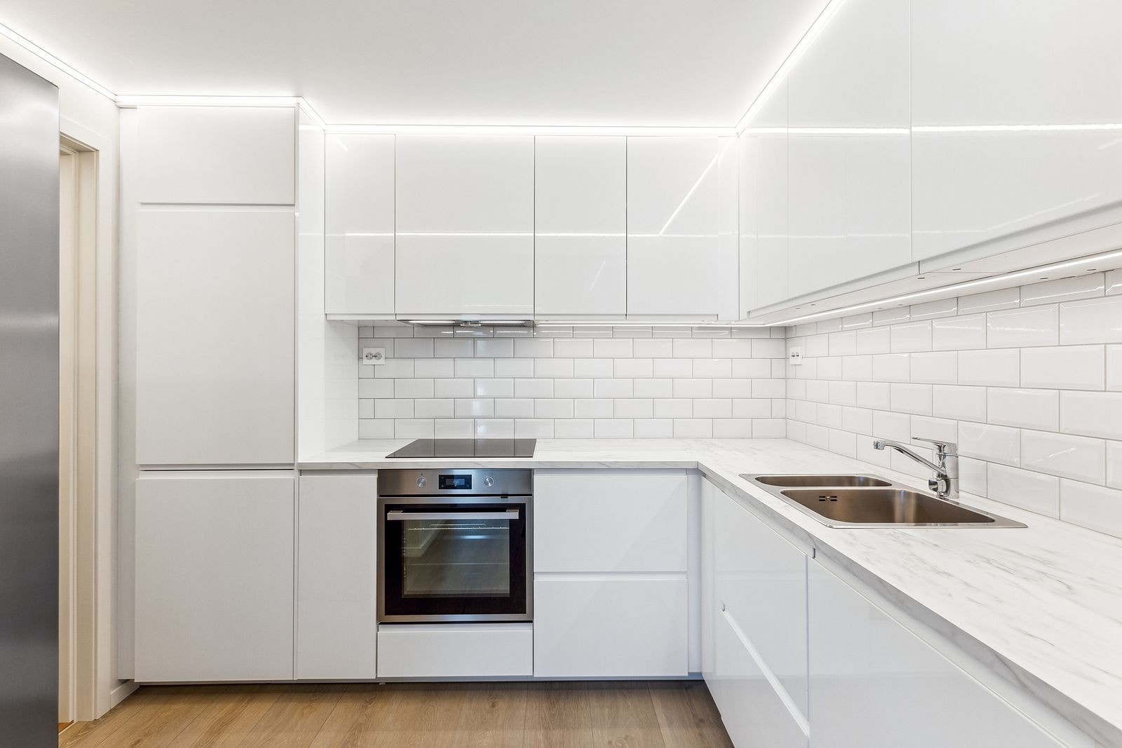 Pent kjøkken med integrerte hvitevarer og frittstående kjøleskap. Godt med skap- og benkeplass. Galleribilde