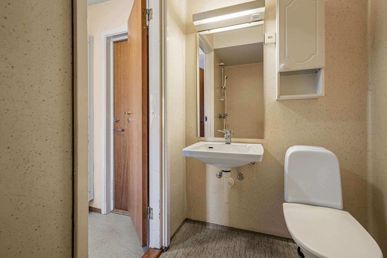 Rommet har gulvvarme og er innredet med en enkel servant med tilhørende overskap og speil. Dusjnisje med forheng, og ventilasjonen skjer via mekanisk avtrekk til felles sentralavtrekksanlegg i bygningen. Galleribilde