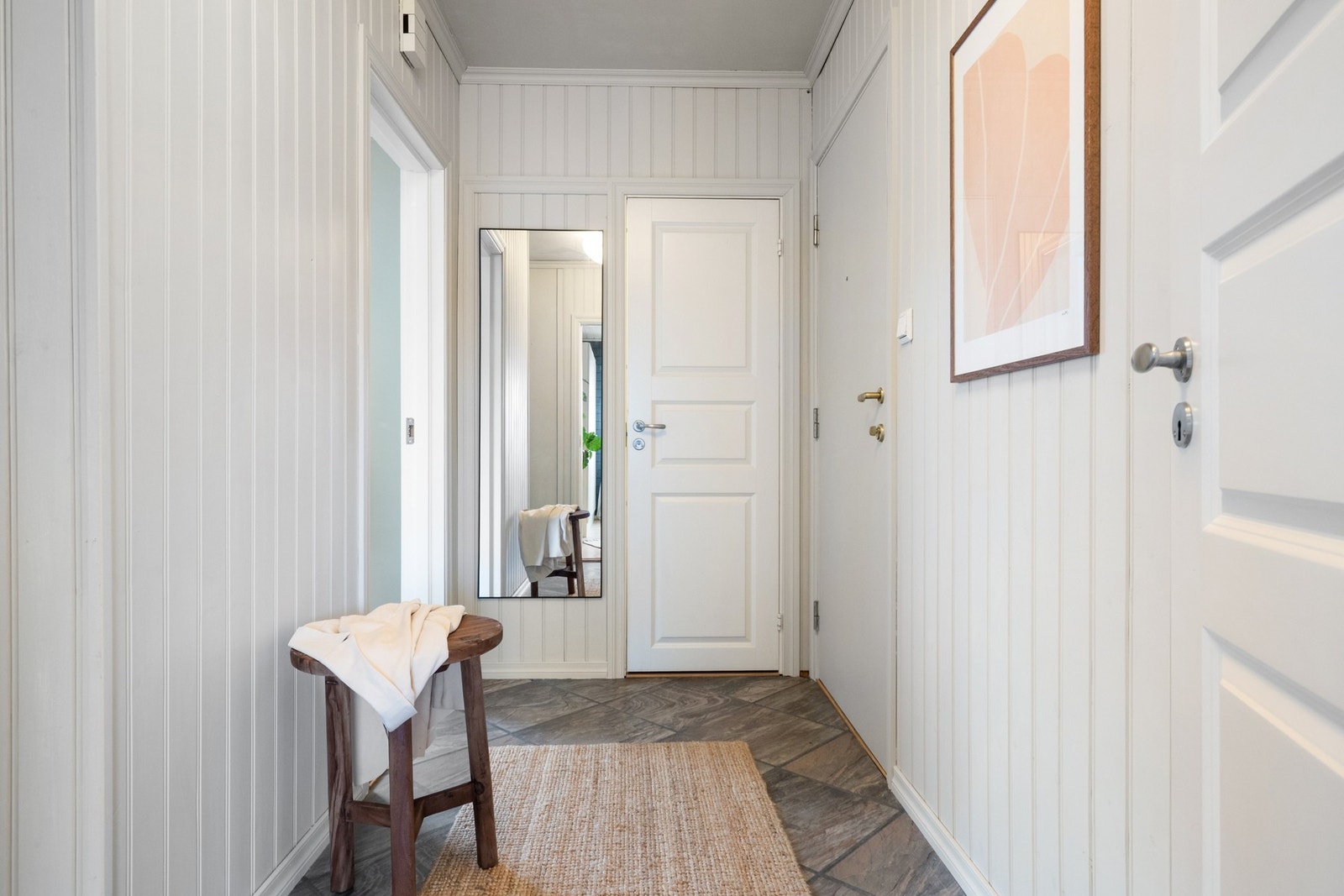 Entréen har vannfast laminat med steinstruktur og lysmalte panelvegger som gir et lyst og trivelig førsteinntrykk. Galleribilde