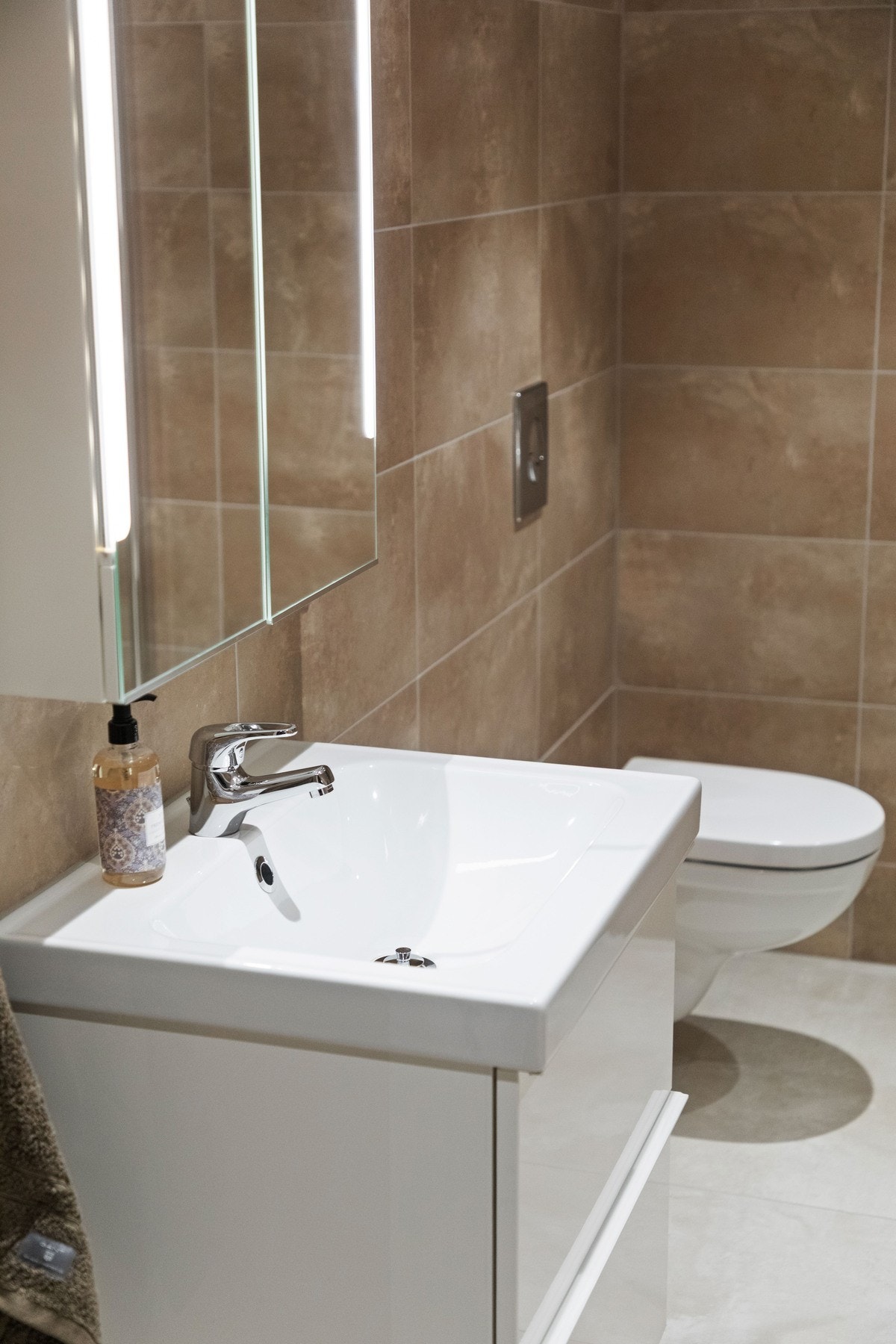 Baderomsinnredningen består av servant med hvite skuffer og speilskap med integrert belysning. Galleribilde