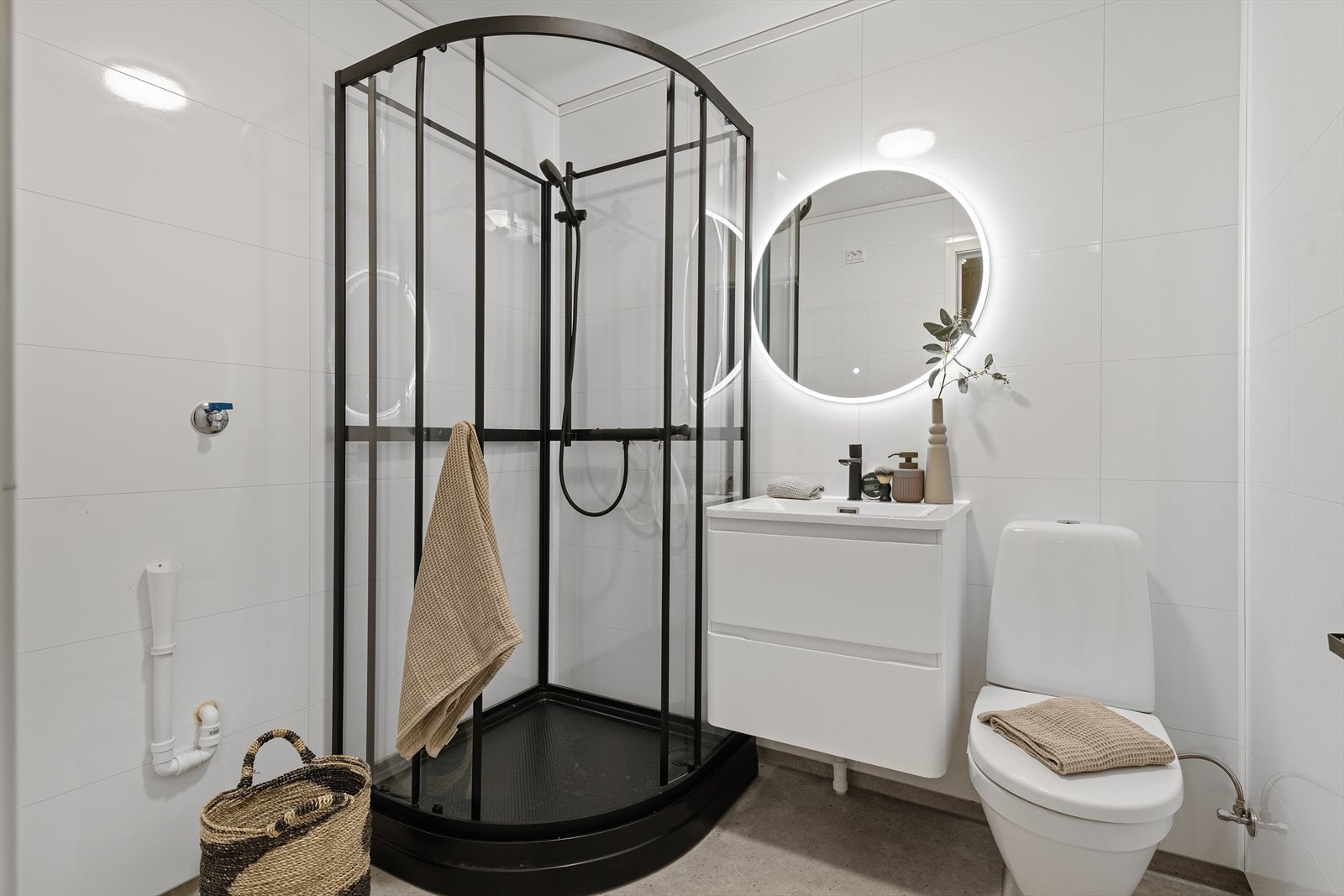 Funksjonelt bad med dusjkabinett, servant i innredning, toalett og praktisk vannuttak for vaskemaskin. Galleribilde