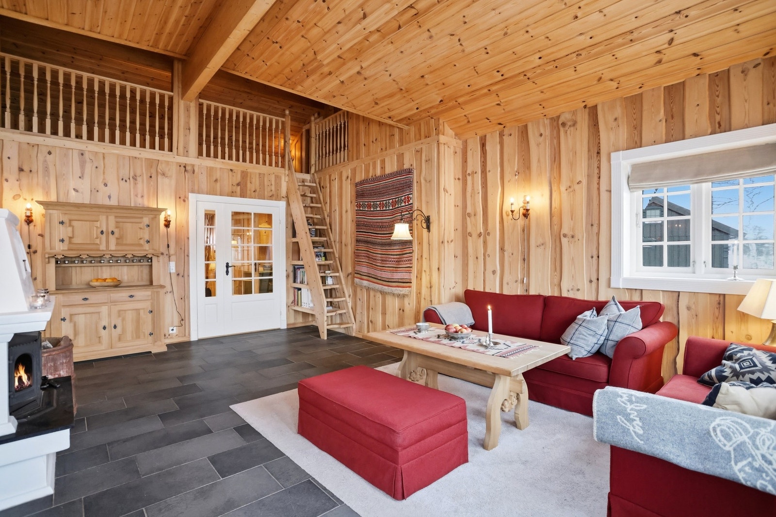 I rommet har du både peis og varmepumpe, noe som sørger for god temperatur. Trapp opp til loftsetasje. Legg merke til den smarte hylleløsningen under trappen Galleribilde